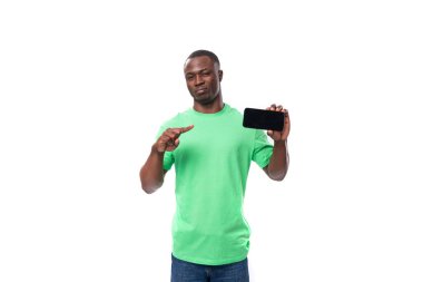 Genç lider, yeşil tişört ve kot giyen Afrikalı adam cep telefonu ekranını gösteriyor..