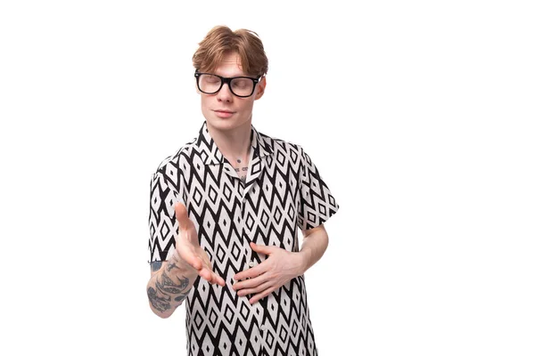 stock image European young man with golden hair and a tattoo on his arms, dressed in a summer black and white shirt, looks attentively with glasses.