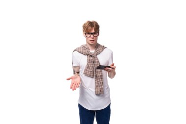 Gömlek giyen kızıl saçlı beyaz bir genç aktif olarak akıllı telefon kullanıyor..