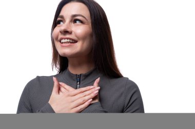 Siyah saçlı, beyaz arka planda gülümseyen mutlu, genç ve şık bir kadın..