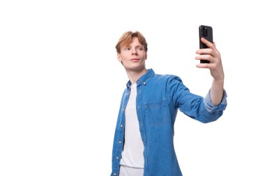 Kendine güveni tam, mavi kot gömlekli, altın saçlı genç bir Avrupalı selfie çekiyor..