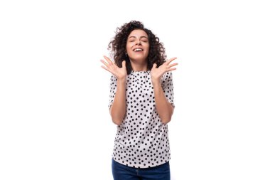 Genç bakımlı, kıvırcık saçlı, bezelye desenli bluz giymiş bir kadın..