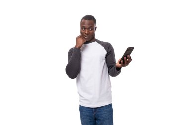 Uzun kollu süveter giymiş kısa saçlı, akıllı telefon tutan genç bir Amerikalı..