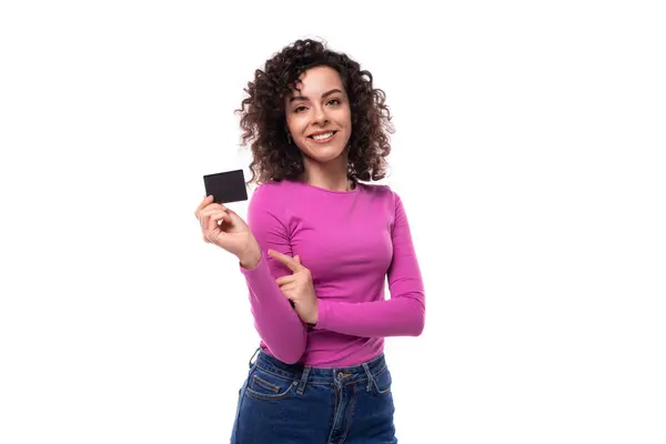 stock image young well-groomed stylish curly brunette lady dressed in a purple turtleneck holds a credit card. e-business concept.