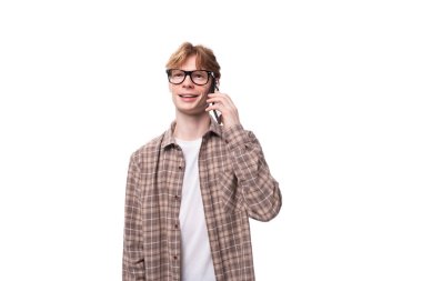 Kızıl saçlı, gözlüklü genç beyaz adam telefonda konuşuyor..