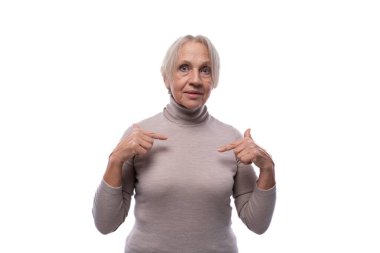 65 yaşında, kısa saçlı, parmaklarıyla işaret eden emekli bir kadın..