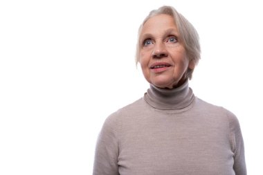 Gri saçlı olgun bir kadın hayal kuruyor ve yukarı bakıyor..