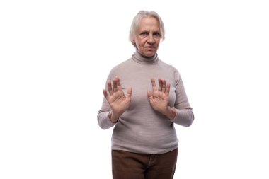 65 yaşında, kısa saçlı, emekli bir kadın öfkesini dile getiriyor..