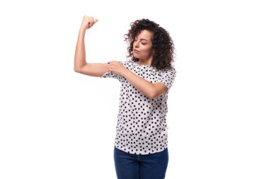 Çekici, genç, esmer, kıvırcık kadın. Üzerinde bezelye deseni olan bir bluz giymişti..