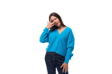 Genç, narin Avrupalı, mavi hırka giymiş, beyaz arka planda düğmeleri olan, fotokopi alanı olan esmer bir kadın..