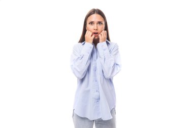 Siyah düz saçlı, mavi bluz giymiş, beyaz, genç bir kadın kameraya şaşkınlıkla bakıyor..