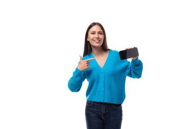 Mavi V yaka kazak giymiş genç, güzel esmer bayan elinde akıllı bir telefon ve fotokopi alanı olan beyaz bir arka plan var..