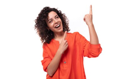 Turuncu tişört giymiş genç, güzel esmer kadın elleriyle işaret ediyor. reklam kavramı.