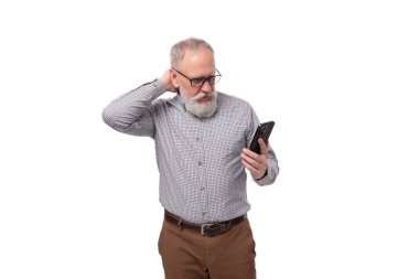 Gri sakallı ve bıyıklı yaşlı adam telefonu çözmeye çalışıyor..