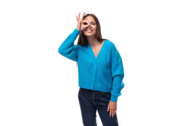 İnce, esmer bir kadının portresi. Beyaz arka planda mavi bir hırka giymiş açık renk bir kadın..