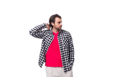 Genç, vahşi, sakallı, esmer adam beyaz arka planda, fotokopi alanı olan bir gömlek giyiyor..