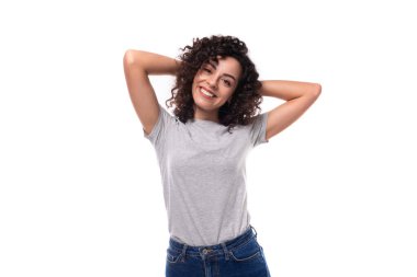 Genç, gülümseyen, esmer, kıvırcık, gri tişörtlü, beyaz arka planda fotokopi alanı olan bir kadın..