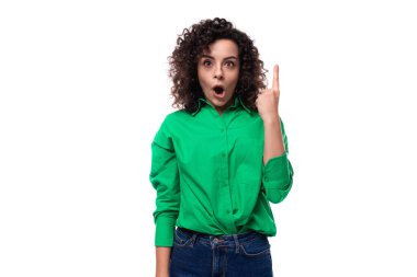 Siyah kıvırcık saçlı, yeşil bluz giymiş genç bir kadın parmaklarını havaya kaldırıyor..