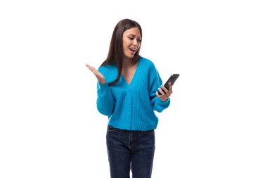 Mavi kazaklı, düğmeli genç esmer kadın akıllı telefondan ne cevap vereceğini düşünüyor..