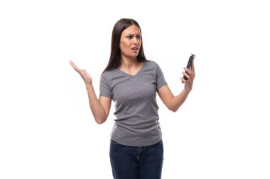 Gri tişörtlü esmer lider kadın beyaz arka plandaki akıllı telefon ekranına fotokopi alanı ile bakıyor..