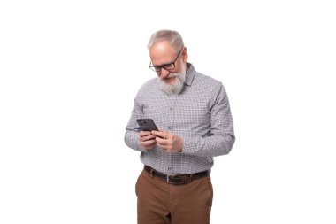Akıllı, başarılı, olgun, gri saçlı, bıyıklı, sakallı bir ofis çalışanı akıllı telefondan sohbet ediyor..