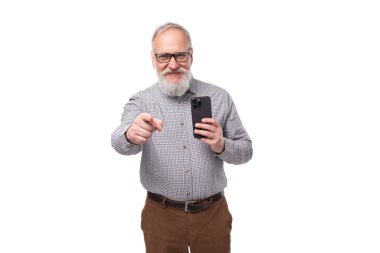Beyaz sakallı ve bıyıklı büyükbaba gömlek giyiyor ve pantolon yeni teknolojilerde ustalaşıyor. Akıllı telefon tutan adam..