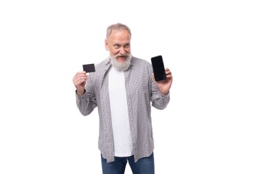 Beyaz sakallı ve bıyıklı, rahat bir gömlek giymiş, elinde plastik kart maketi ve akıllı telefonu olan yakışıklı, olgun bir adam..