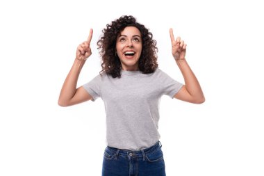 Otantik kıvırcık saçlı, gri tişörtlü esmer kadın ellerini reklam alanına uzatıyor..