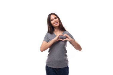 Genç, güler yüzlü, ince esmer organizatör. Gri tişörtlü, beyaz arka planda baskı için yeri olan bir kadın..