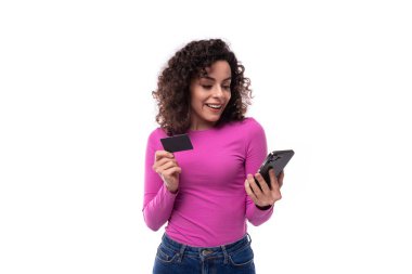 Leylak rengi ceket giymiş kıvırcık siyah saçlı genç ve güzel lider kadın telefonunda internet bankacılığı kullanıyor. e-iş konsepti.