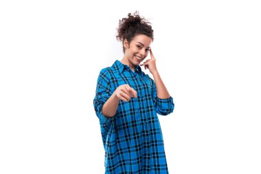 Saçları topuz şeklinde toplanmış beyaz, esmer bir kadın açık mavi bir gömlek giyiyor..