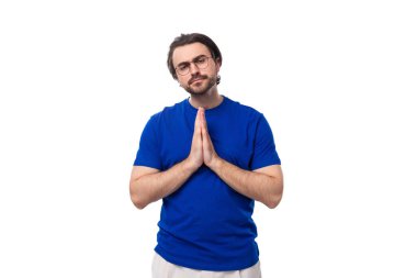 Genç, esmer, Avrupalı, bakımlı, mavi tişörtlü, sakallı bir adam..