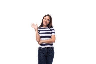 İnce, esmer, beyaz kadın portresi. Hafif makyajlı, çizgili tişört ve kot pantolon giymiş. Ellerini sallıyor..