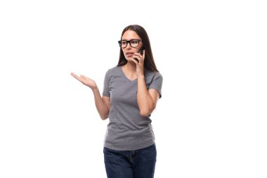 Gri tişörtlü, esmer, Avrupalı bir kadın telefonda konuşuyor..