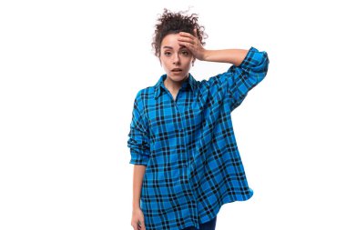 Genç üzgün kıvırcık esmer kadın mavi ekose gömlekli beyaz arka planda.