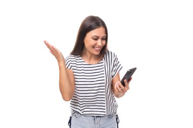 30 yaşında uzun düz saçlı güzel esmer model bir kadın gülümseyen bir cep telefonuna bakıyor..