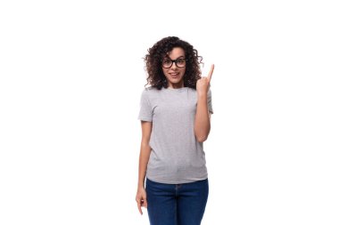 Genç, tatlı, esmer, kıvırcık, gözlüklü, sıradan kot pantolon ve tişörtlü beyaz arka planda izole edilmiş, basılabilir maketli beyaz kadın..