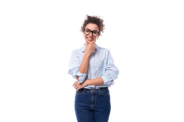 Topuz içinde toplanmış kıvırcık siyah saçlı, genç ve zeki patron kadın arka planda mavi gömlek ve kot pantolon giyiyor ve arka planda fotokopi alanı var..