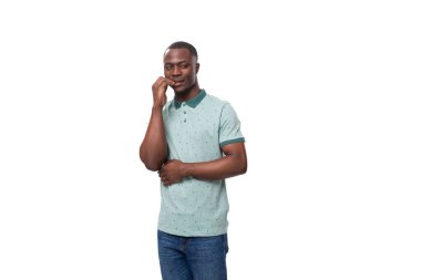 Genç, yakışıklı, gülümseyen Afrikalı bir adam. Kafasını tutarak düşünüyor..