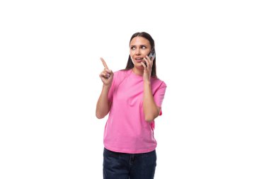 Pembe tişört giyen, siyah saçlı, güzel görünümlü genç bir kadın telefonda konuşuyor..