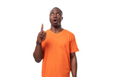 Genç, ilham verici, turuncu tişört giyen Afrikalı adam haberleri sunar..