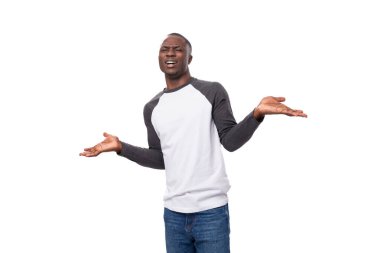 Siyah beyaz kazak giymiş, kameraya poz veren zayıf Afrikalı genç adam..