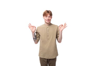 Bej gömlekli genç kızıl saçlı adam beyaz arka plan üzerinde meditasyon yapıyor..