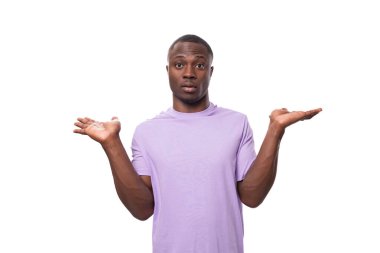 Eflatun tişörtlü genç pozitif Amerikalı adam beyaz arka plandaki bir fikir ve başarıdan esinlenir..