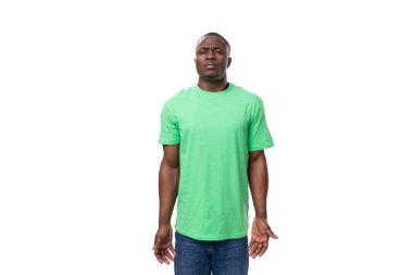 Açık yeşil tişört giymiş 30 yaşındaki Amerikalı adam düşünceli bir şekilde kameraya bakar..