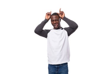 Beyaz bir arka planda siyah beyaz eşofman üstü giymiş, kendine güveni tam genç bir Amerikalı..