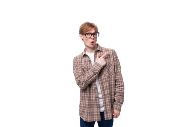Gözlüklü, kızıl saçlı, ekose gömlekli, elleri yanda genç, beyaz bir adam..