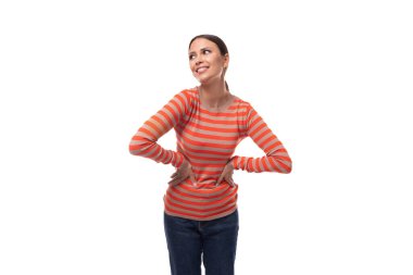 Turuncu kazak giymiş, siyah saçlı, genç ve güzel bir kadın ellerini belinde tutuyor..