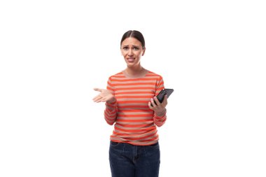 Dar turuncu kazak giymiş çekici, genç bir esmer kadın elinde telefonla omuz silkiyor..