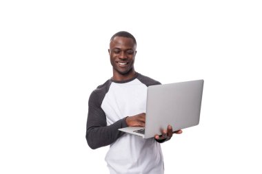 Genç Amerikalı sıradan giyinmiş bir adam dizüstü bilgisayar kullanıyor..